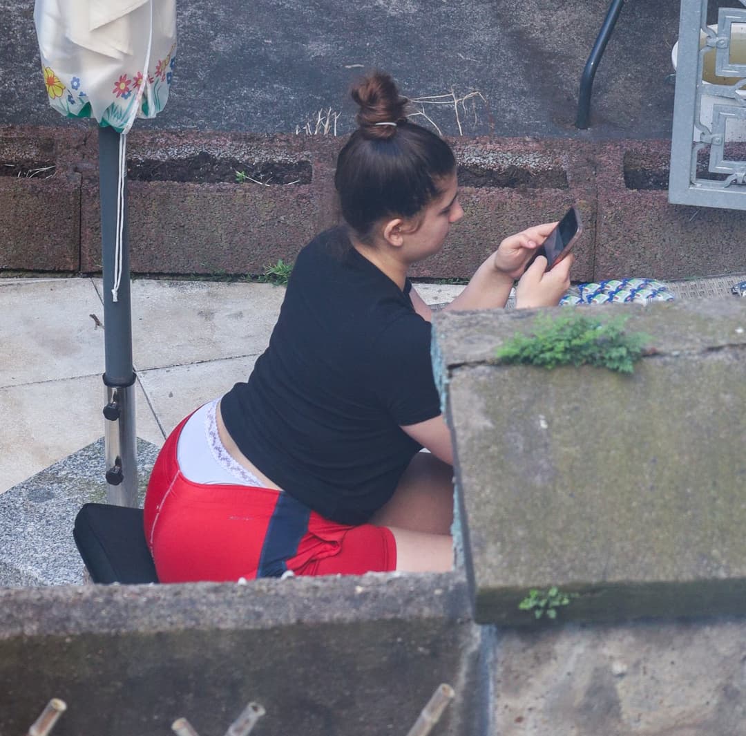 Chubby chick shows her thong while looking at her phone