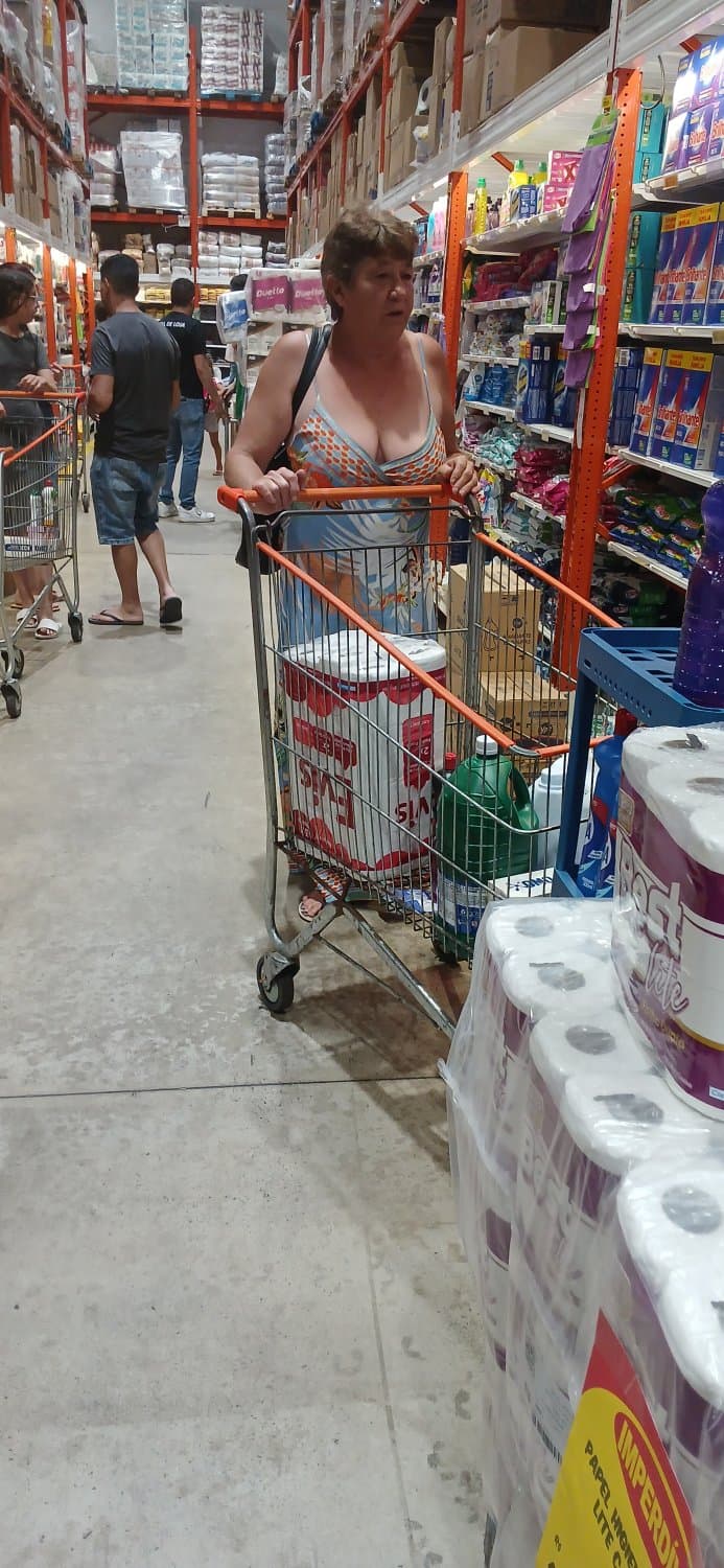 Old woman wearing a dress without a bra and with a very low neckline.