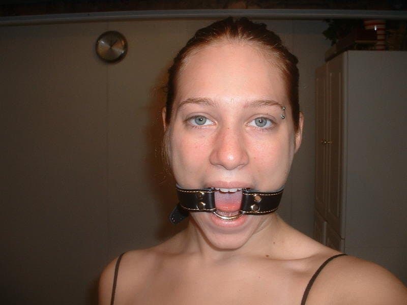 Submissive Redhead with massive jugs poses with her ball gag