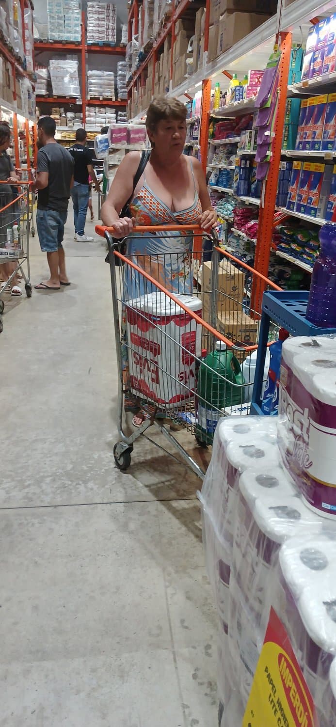 Old woman wearing a dress without a bra and with a very low neckline.