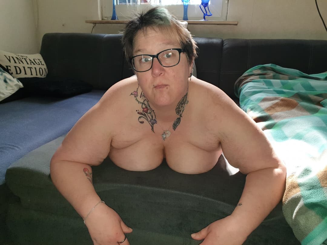 Old woman with tattoos and piercings showing off